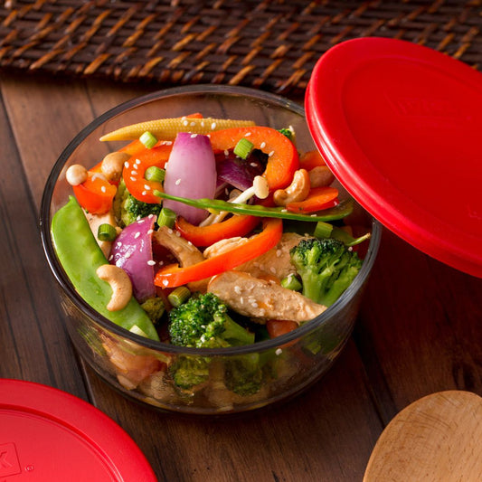 Glass container with a colorful salad on a wooden surface