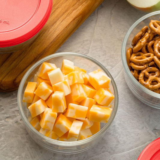 Bowl of cheese cubes next to a bowl of pretzels on a gray surface.