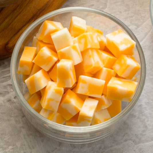 Glass bowl filled with cubed cheese on a neutral background