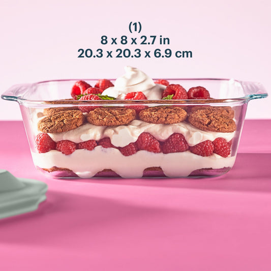Glass baking dish with dessert layers on a pink background