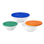 Set of three glass bowls with colorful lids on a white background